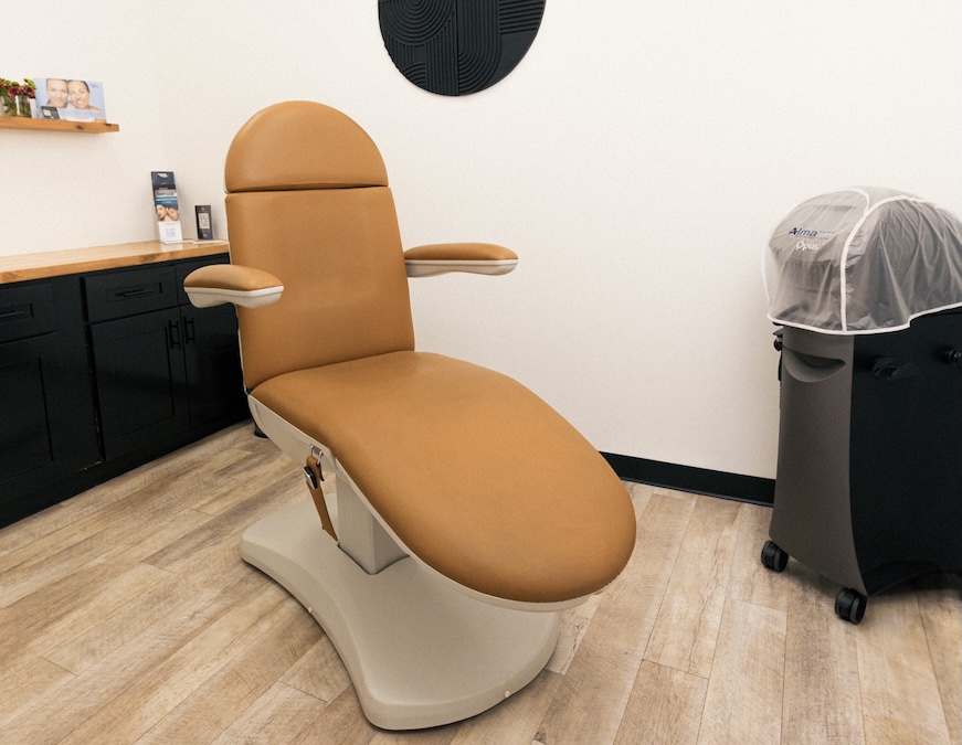 A comfortable reclining treatment chair sits in the center of a modern, aesthetic treatment room for BBL photofacial in Georgetown.